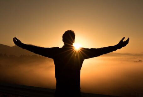 Success Solar - silhouette photo of man on cliff during sunset