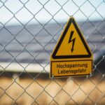 Safety Solar - selective focus photography of danger high voltage signage on chain-link fence