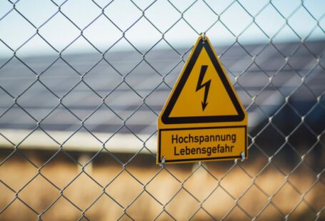 Safety Solar - selective focus photography of danger high voltage signage on chain-link fence