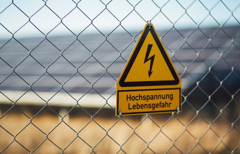 Safety Solar - selective focus photography of danger high voltage signage on chain-link fence