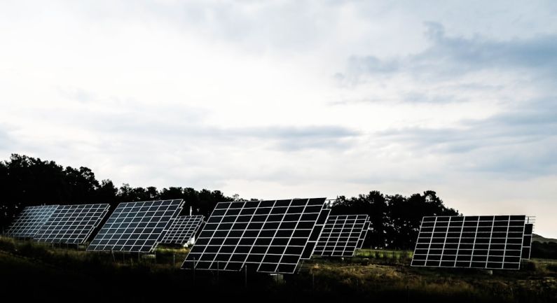 Ecology Solar - silhouette photography of assorted solar panel behind trees