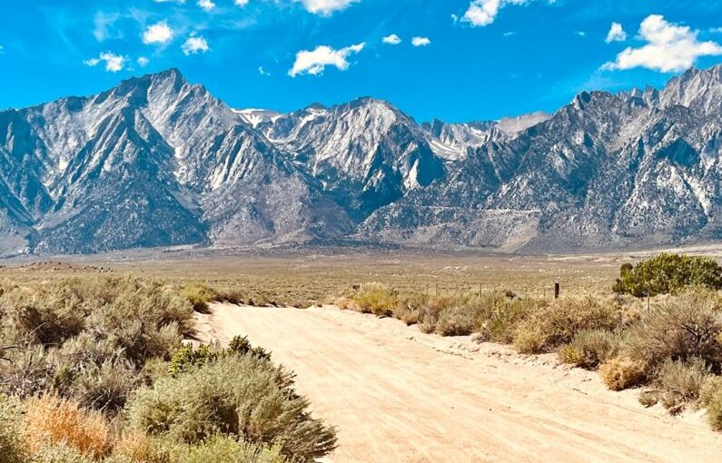 Independence Solar - a dirt road in front of a mountain range