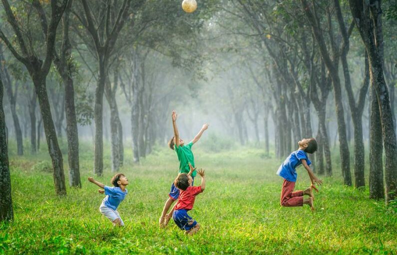 Jakarta Solar - four boy playing ball on green grass