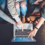 Education Trend - three person pointing the silver laptop computer