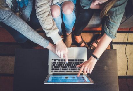 Education Trend - three person pointing the silver laptop computer