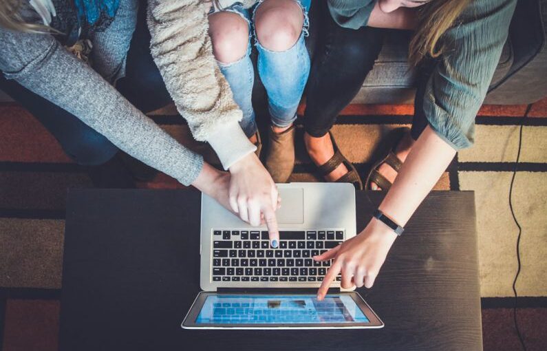 Education Trend - three person pointing the silver laptop computer